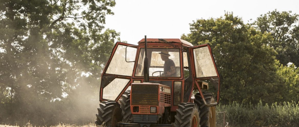 Tractor and straw baler in wheat field, farmer baling straw.